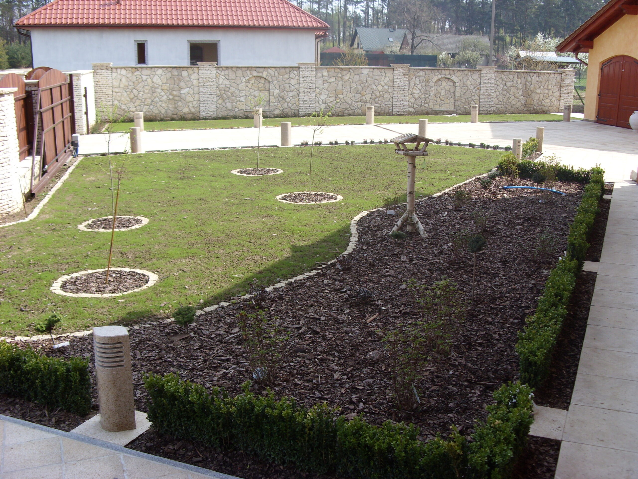 Narożne ogrodzenie z kamienia z drewnianą bramą